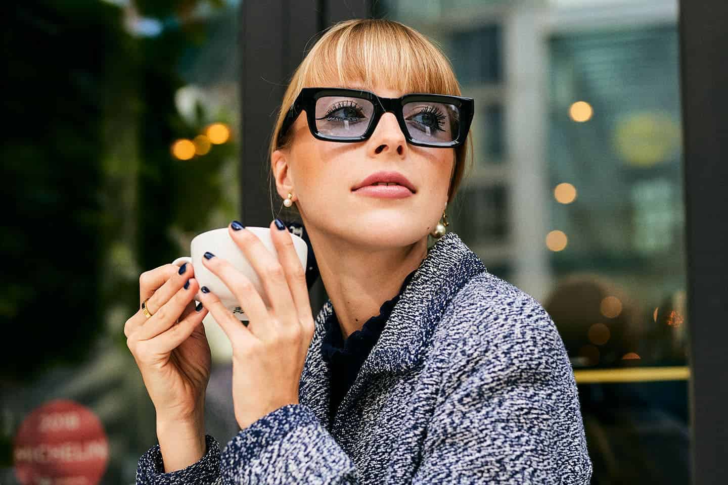 Eine junge Frau sitzt in einem Café in Frankfurt am Main und trinkt einen Kaffee.
