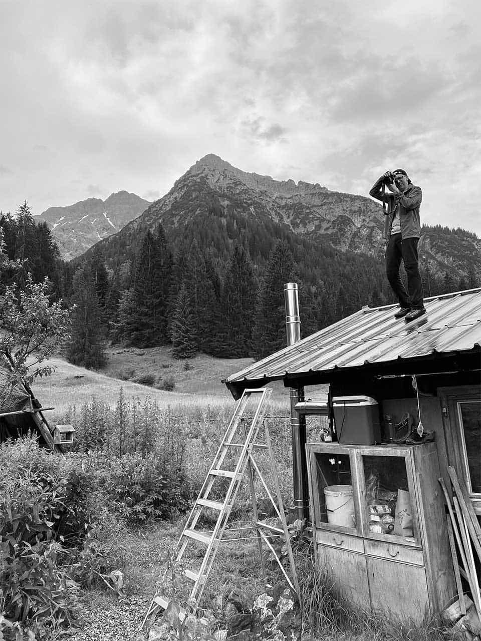 Fotograf Christopher Fuhrmann steht auf dem Dach einer Hütte in den Bergen